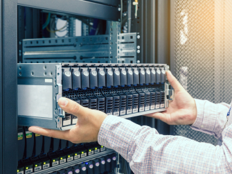 Hände ziehen Rechner aus Serverschrank