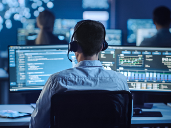 Mann arbeitet vor Analysebildschirm mit Headset