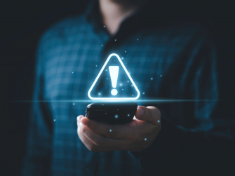 Mann hält Smartphone in der Hand und Ausrufezeichen als Warnung erscheint über dem Handy