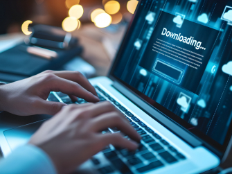 Laptop steht auf Schreibtisch, zwei Hände tippen