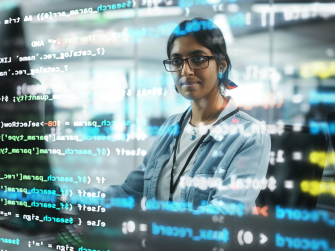 Mit Code beschriftete Glaswand, dahinter steht ein Mensch